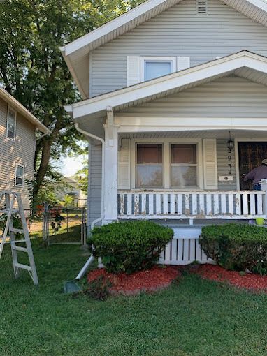 A house with a porch and a ladder in front of it
