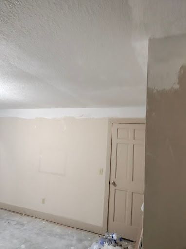 A room with a door and a ceiling that is being painted.