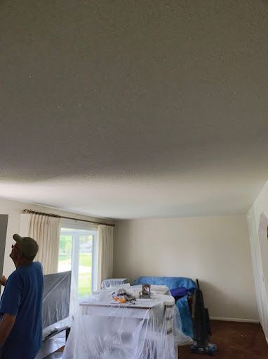 A man is standing in a living room looking up at the ceiling.