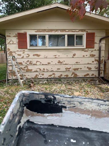 A house is being painted with a bucket of paint in front of it.