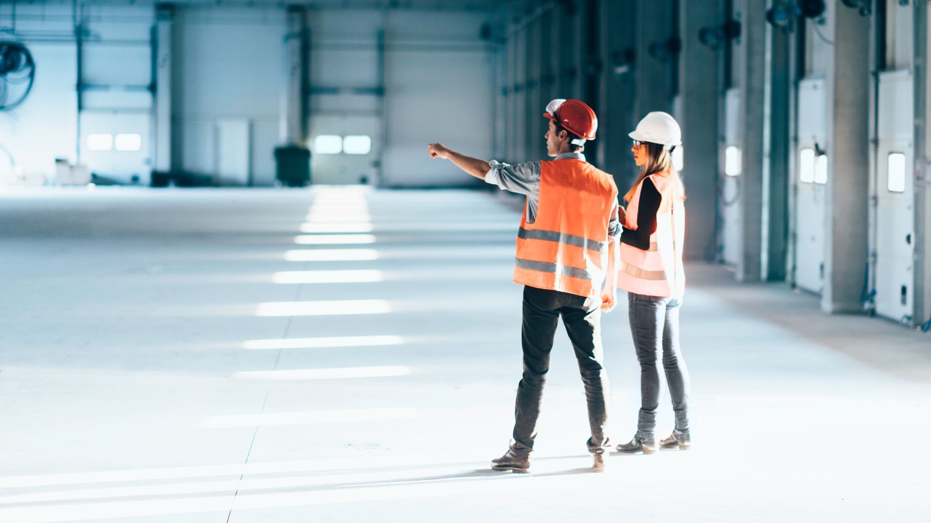 A man and a woman are standing in an empty warehouse.