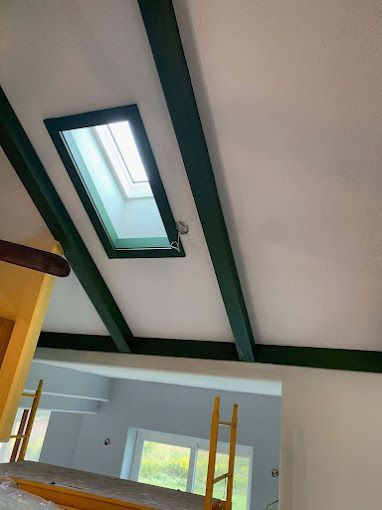 A ceiling with a skylight and green beams