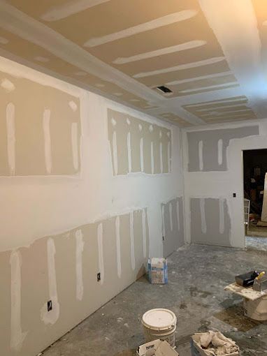 A room with drywall on the walls and a bucket of paint on the floor.