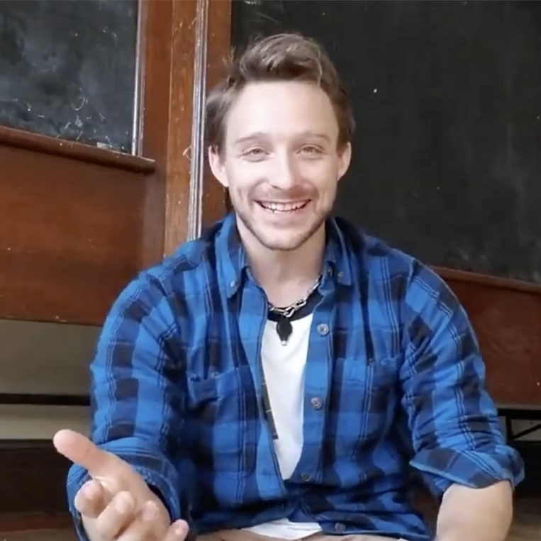 A man wearing a blue plaid shirt is smiling
