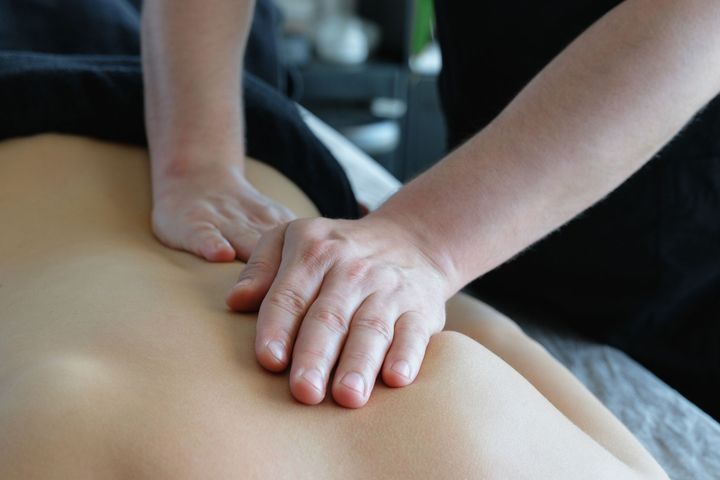 Person receiving a back massage with hands pressing into the lower back.