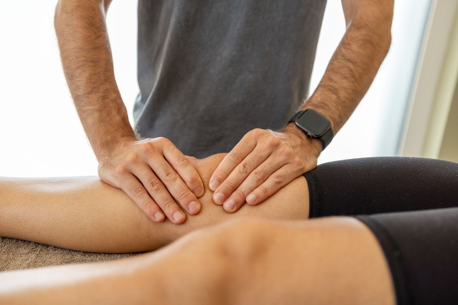 Hands massaging a person's knee. The person is lying down, wearing black leggings. Hands massaging a person's knee. The person is lying down, wearing black leggings.