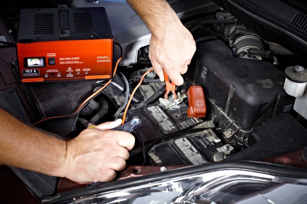 A Person is Charging a Car Battery With a Charger — Sprint Mufflers, Exhausts & Mechanical Repairs in Stuart, NT