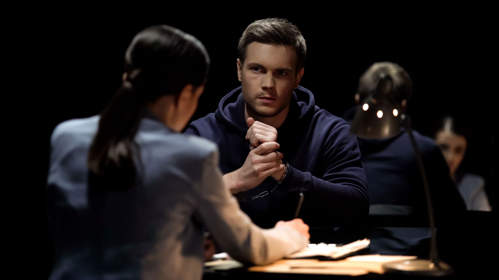 A man is sitting at a table talking to a woman in a dark room.
