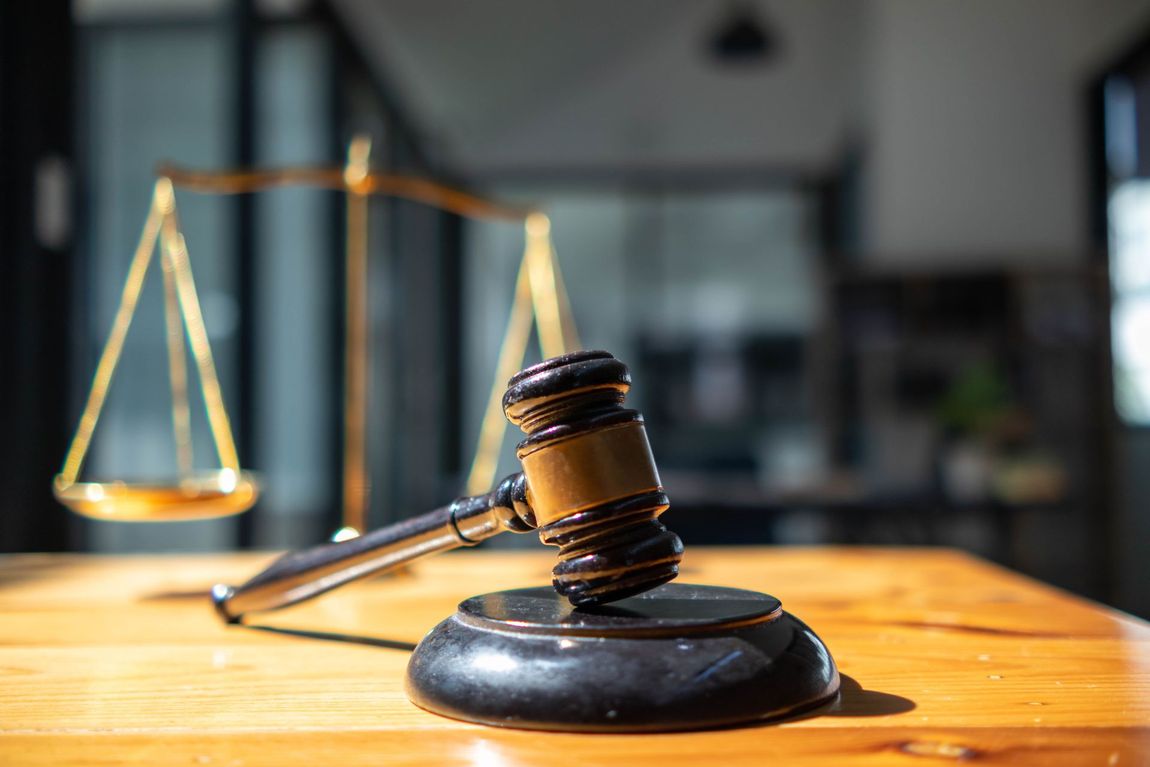 A judge 's gavel and scales of justice are on a wooden table.