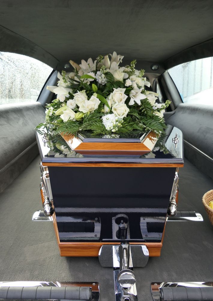 A Coffin With Flowers In It Is In The Back Of A Car — Territory Funerals In Coolalinga, NT