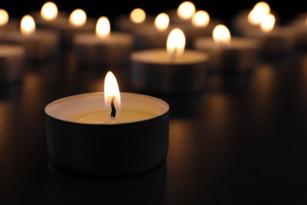 A Group Of Lit Candles Are Sitting On A Table In The Dark — Territory Funerals In Coolalinga, NT