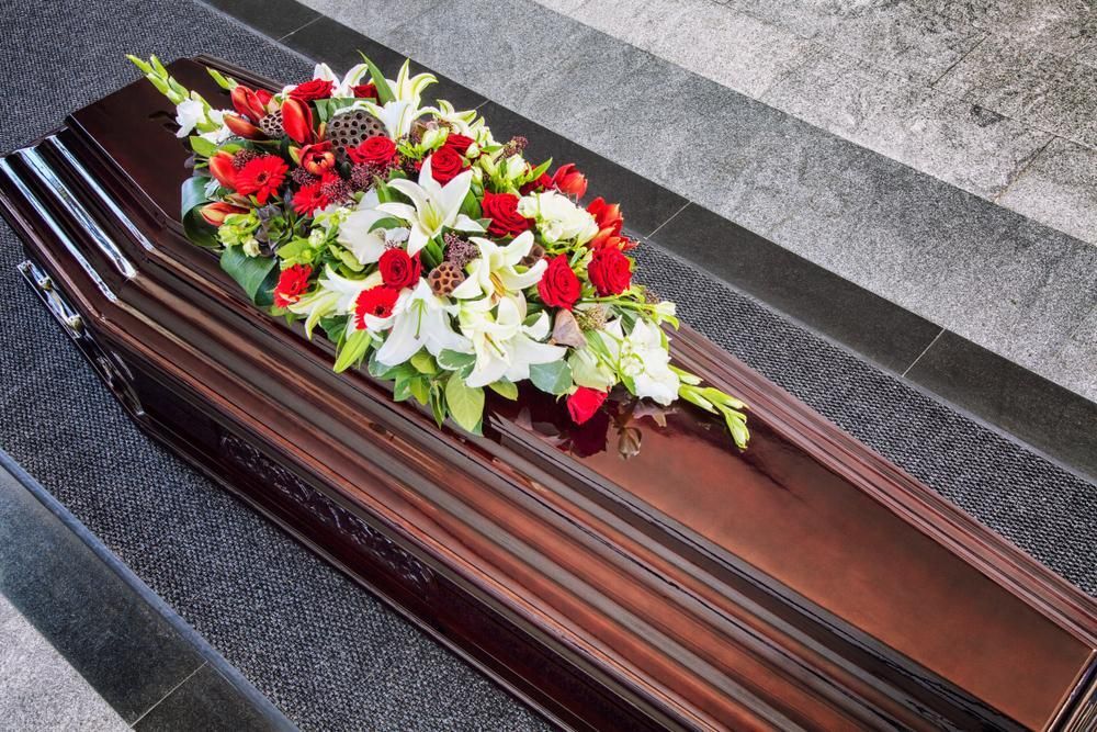 A Coffin With Flowers On It Is Sitting On A Staircase — Territory Funerals In Palmerston, NT