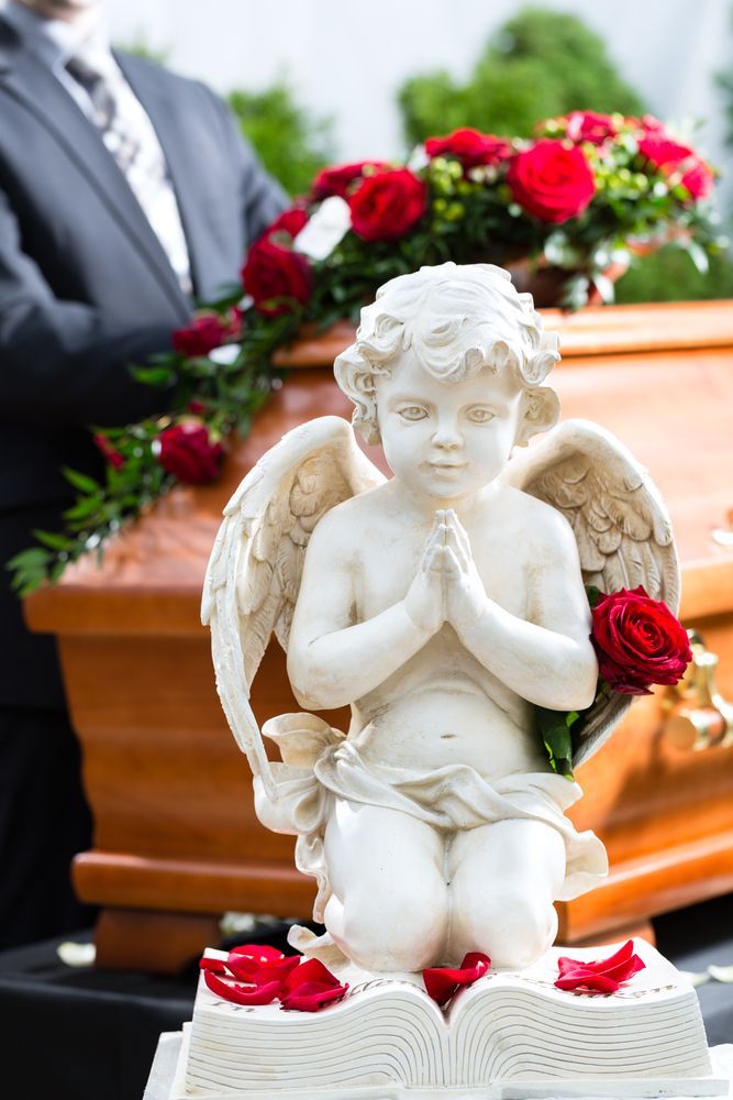 There Is A Statue Of An Angel Holding A Rose In Front Of A Coffin — Territory Funerals In Karama, NT