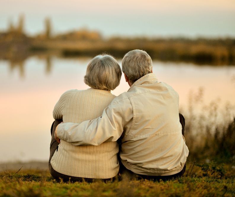 An elderly couple sitting on he edge of a lake— Territory Funerals In Yarrawonga, NT