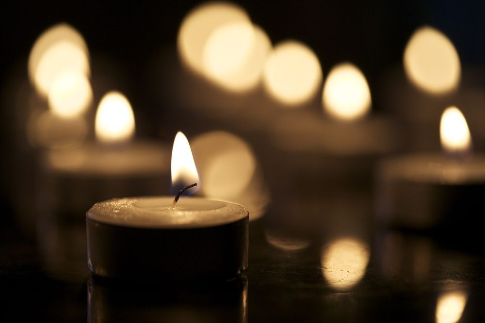 A Group Of Lit Candles Are Sitting On A Table In The Dark — Territory Funerals In Karama, NT