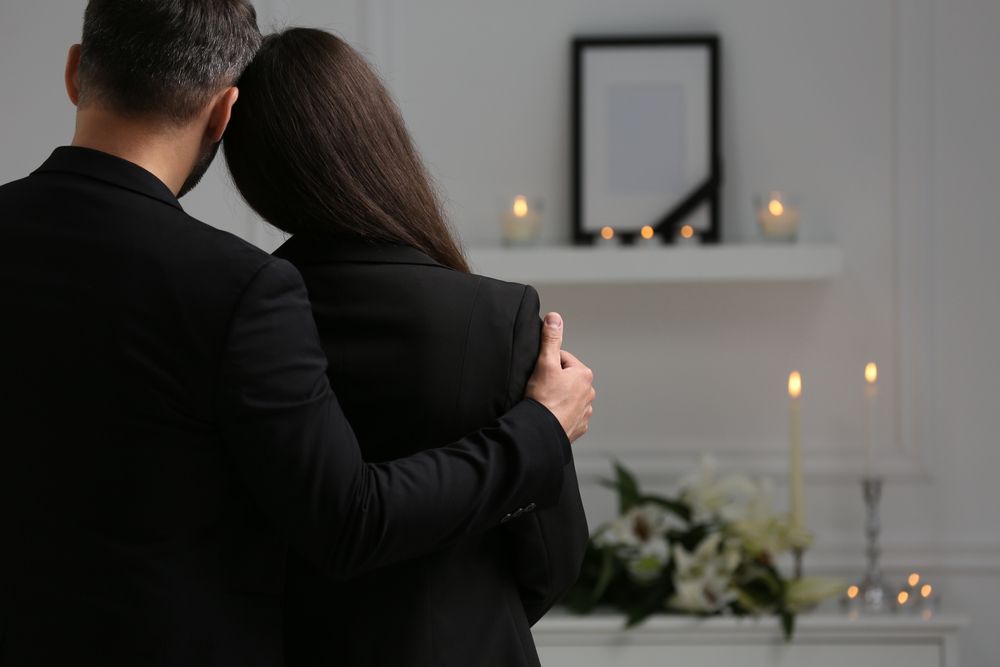 A Man And A Woman Are Standing Next To Each Other At A Funeral — Territory Funerals In Yarrawonga, NT