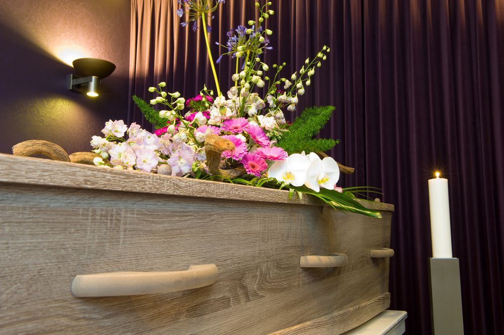 A Wooden Coffin With Flowers On Top Of It In A Funeral Home — Territory Funerals In Yarrawonga, NT