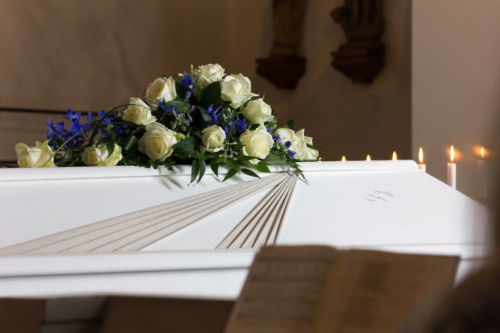 A White Coffin With Flowers And Candles On It In A Church — Territory Funerals In Howard Springs, NT