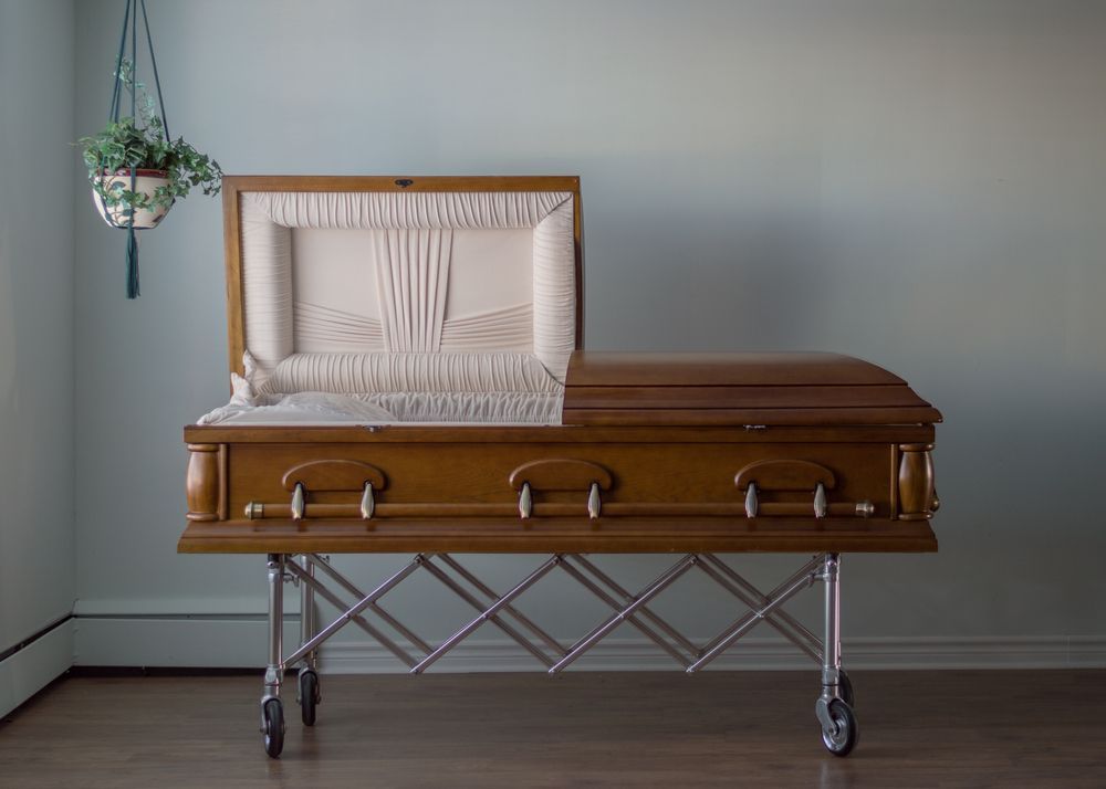 A Wooden Coffin Is Sitting In A Room With The Lid Open — Territory Funerals In Yarrawonga, NT
