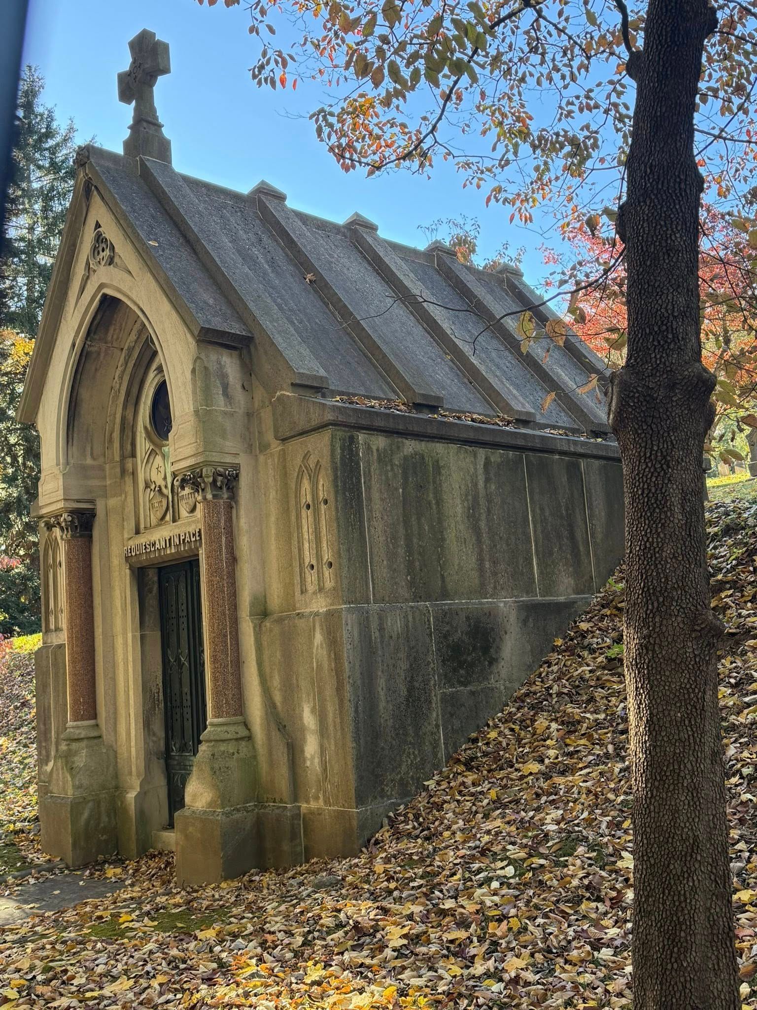 Stone Mausoleum With a Cross on Top, in a Wooded Cemetery