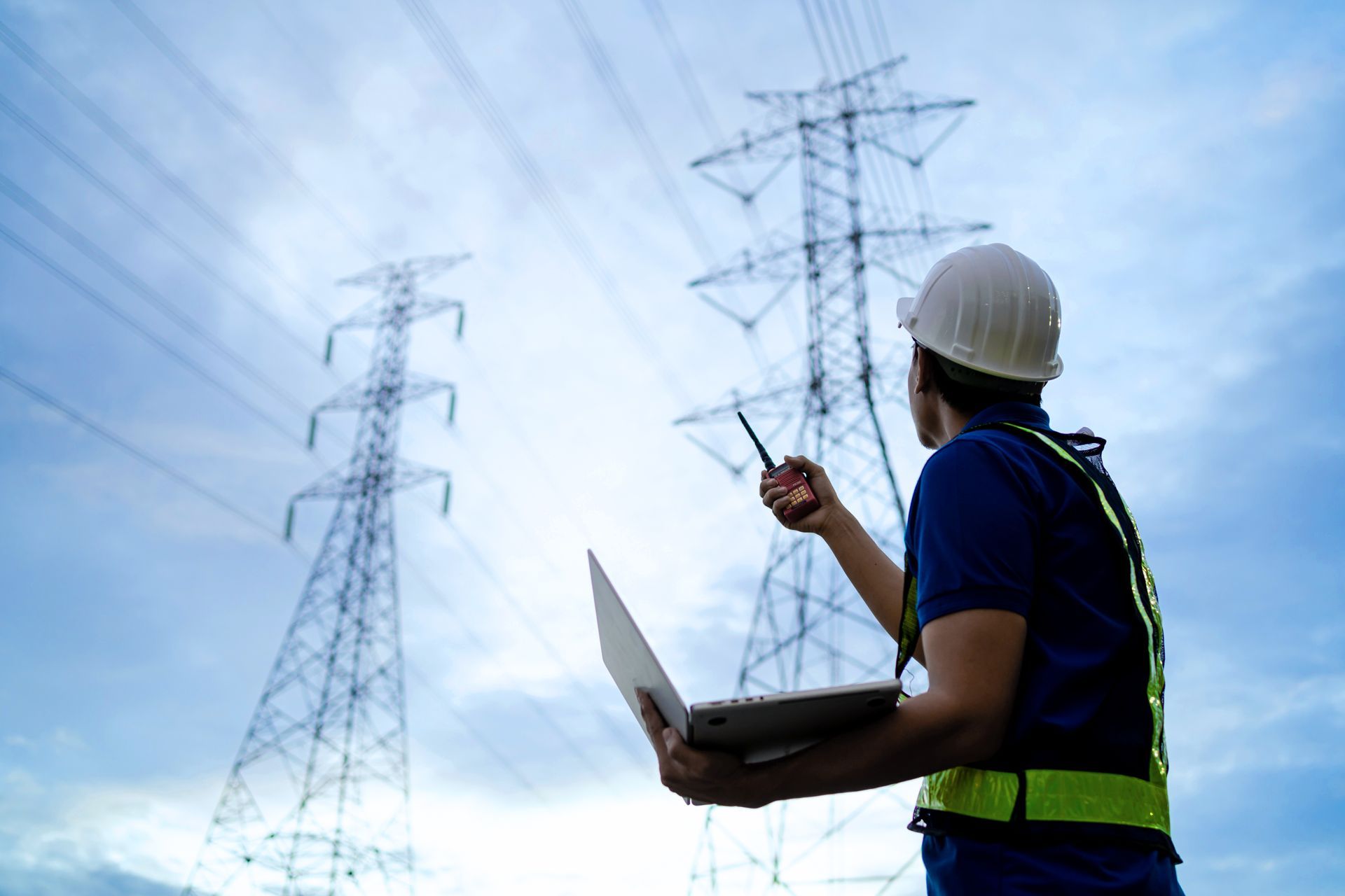 An aerial view of a power substation with electrical equipment, lines, and pylons.