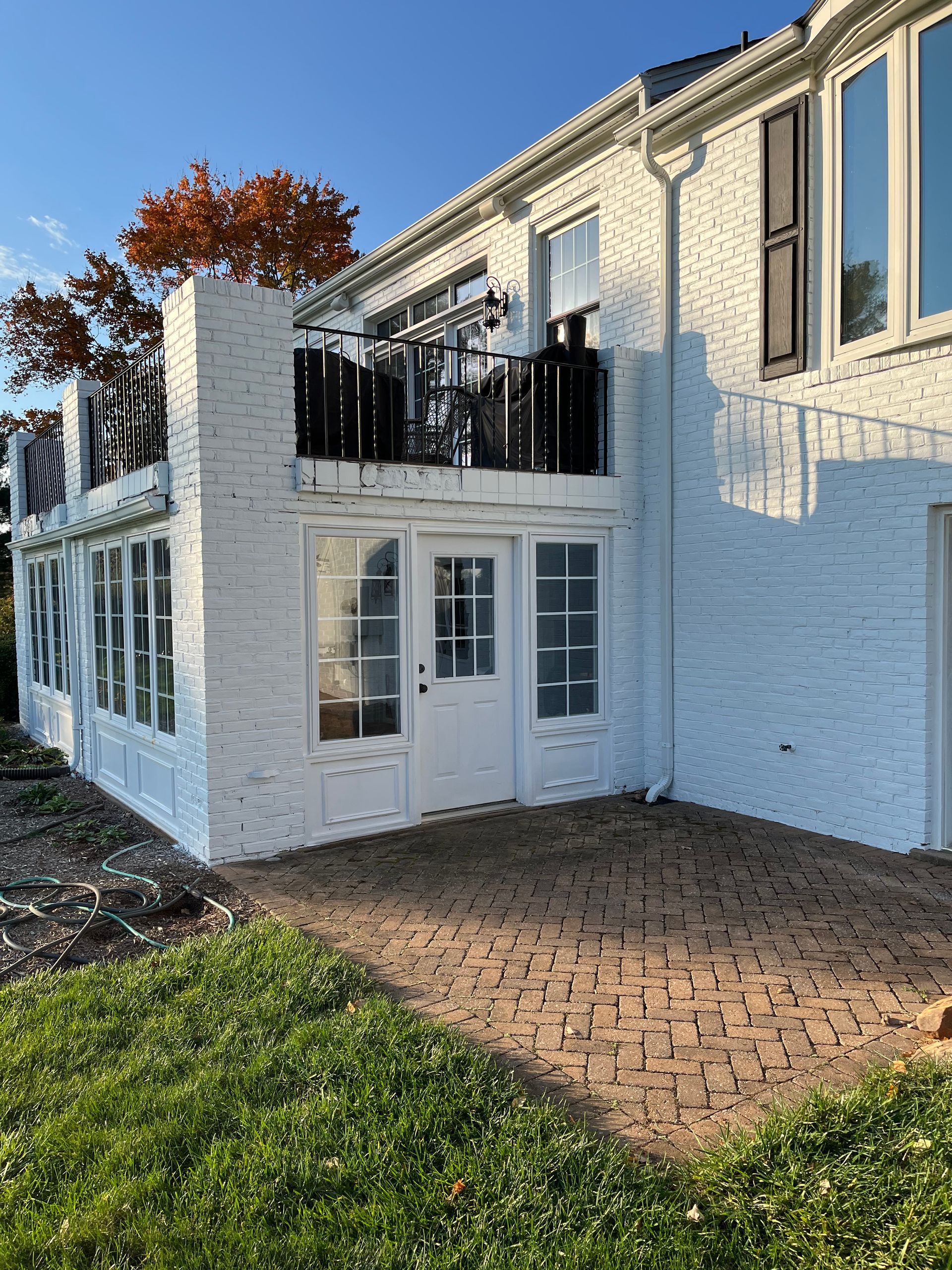 White brick house with a small patio and a balcony.