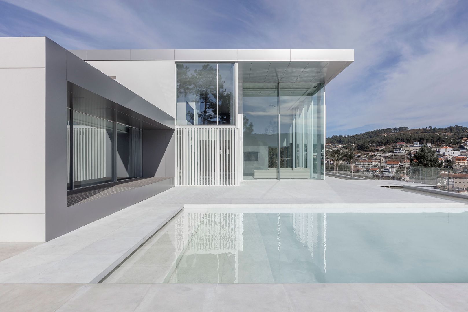 Modern house facade with pool, featuring minimalist windows by OTIIMA, characterized by clean lines and extensive glass areas.