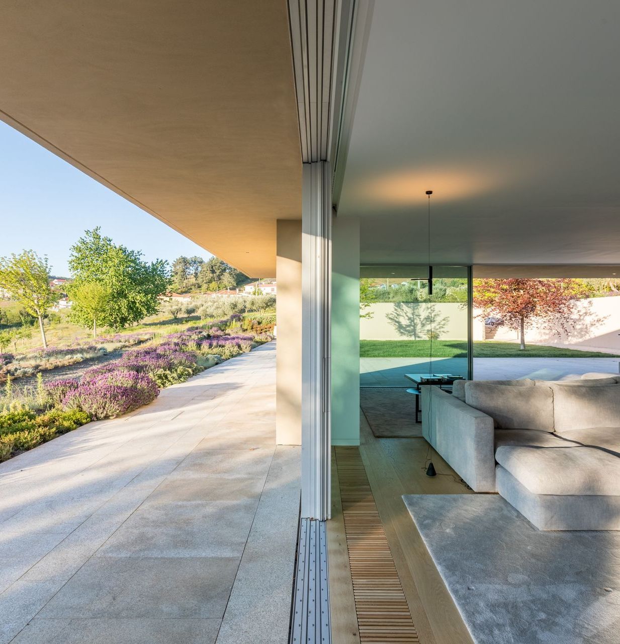 Spacious living room with panoramic glass walls by OTIIMA, offering stunning views of the surrounding landscape.