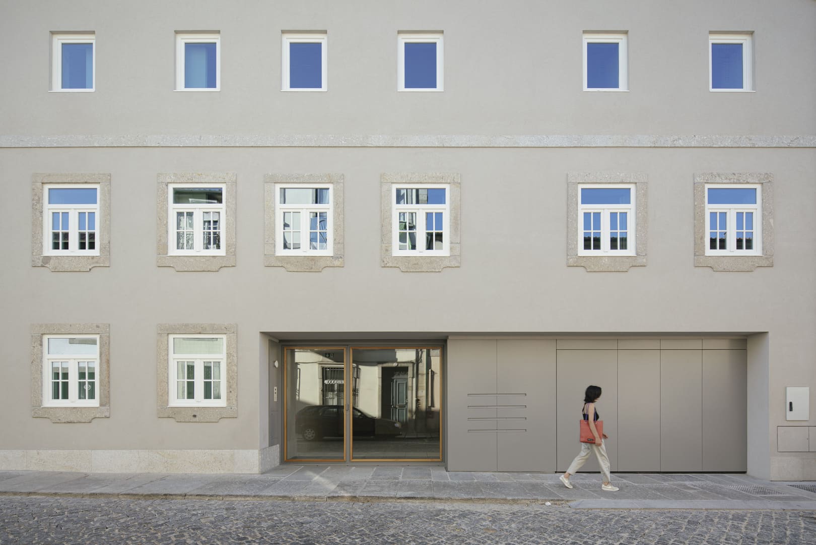 Woman walking past a building with minimalist architecture and modern design