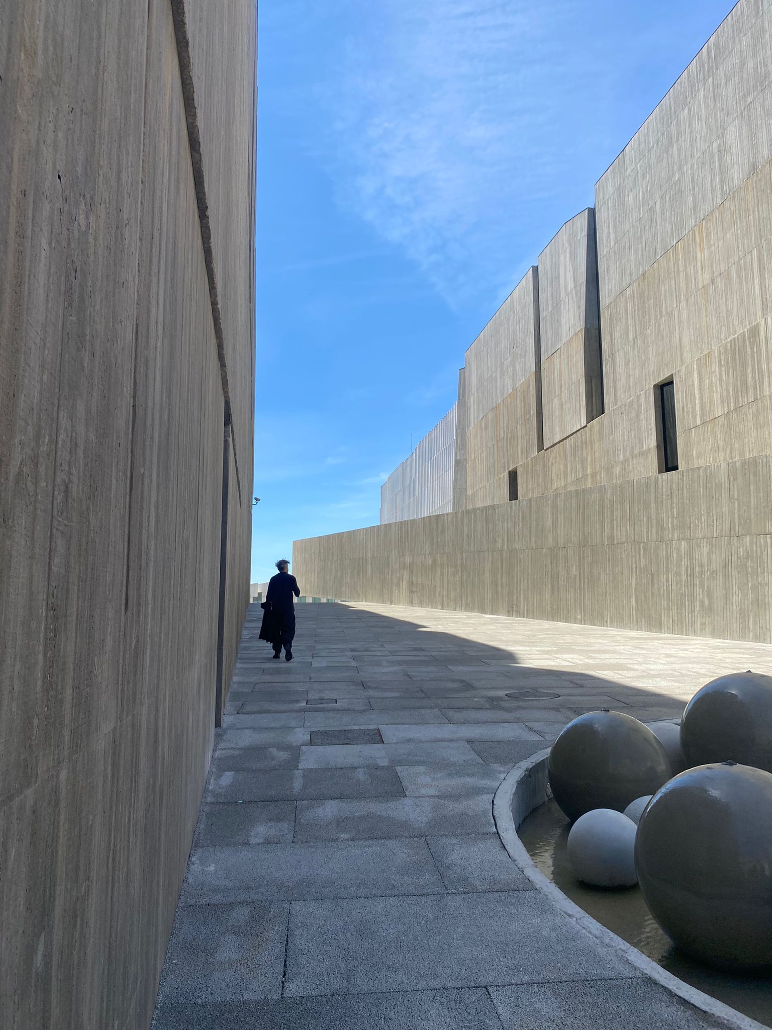 Alejandro Aravena walking along a modern architectural pathway of EDP new Headquarters. 