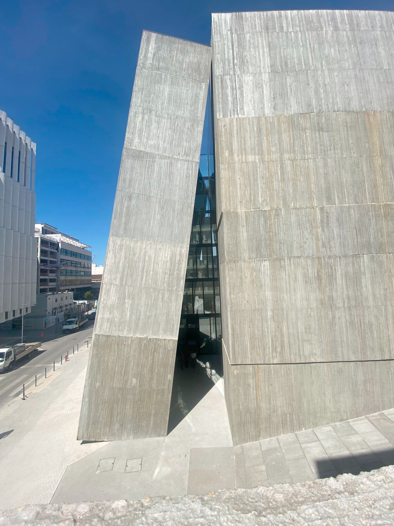 A detailed view of a contemporary building showcasing OTIIMA's minimalist window framing. The large glass panels reflect the surrounding architecture, emphasizing the seamless integration and elegance of OTIIMA's design in modern construction