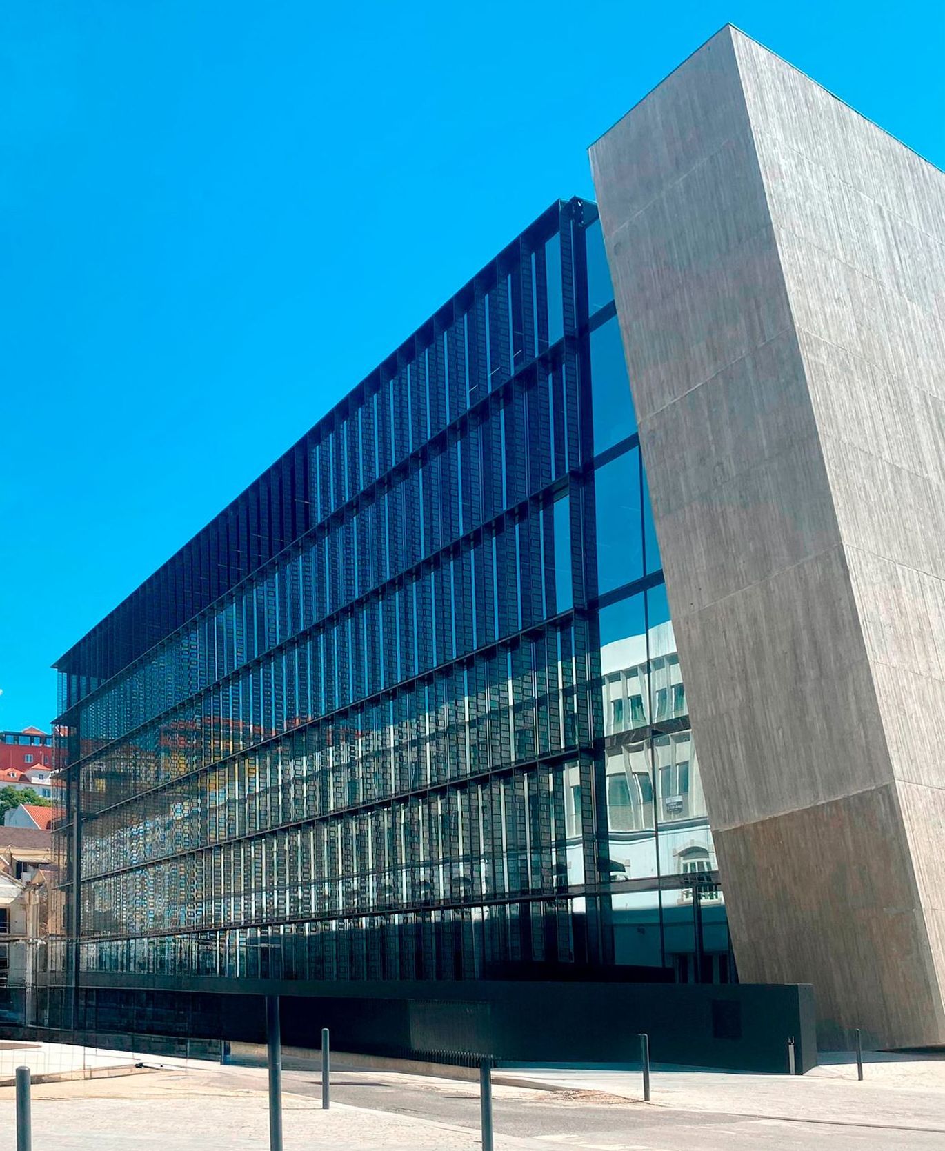 A detailed view of a contemporary building showcasing OTIIMA's minimalist window framing. The large glass panels reflect the surrounding architecture, emphasizing the seamless integration and elegance of OTIIMA's design in modern construction