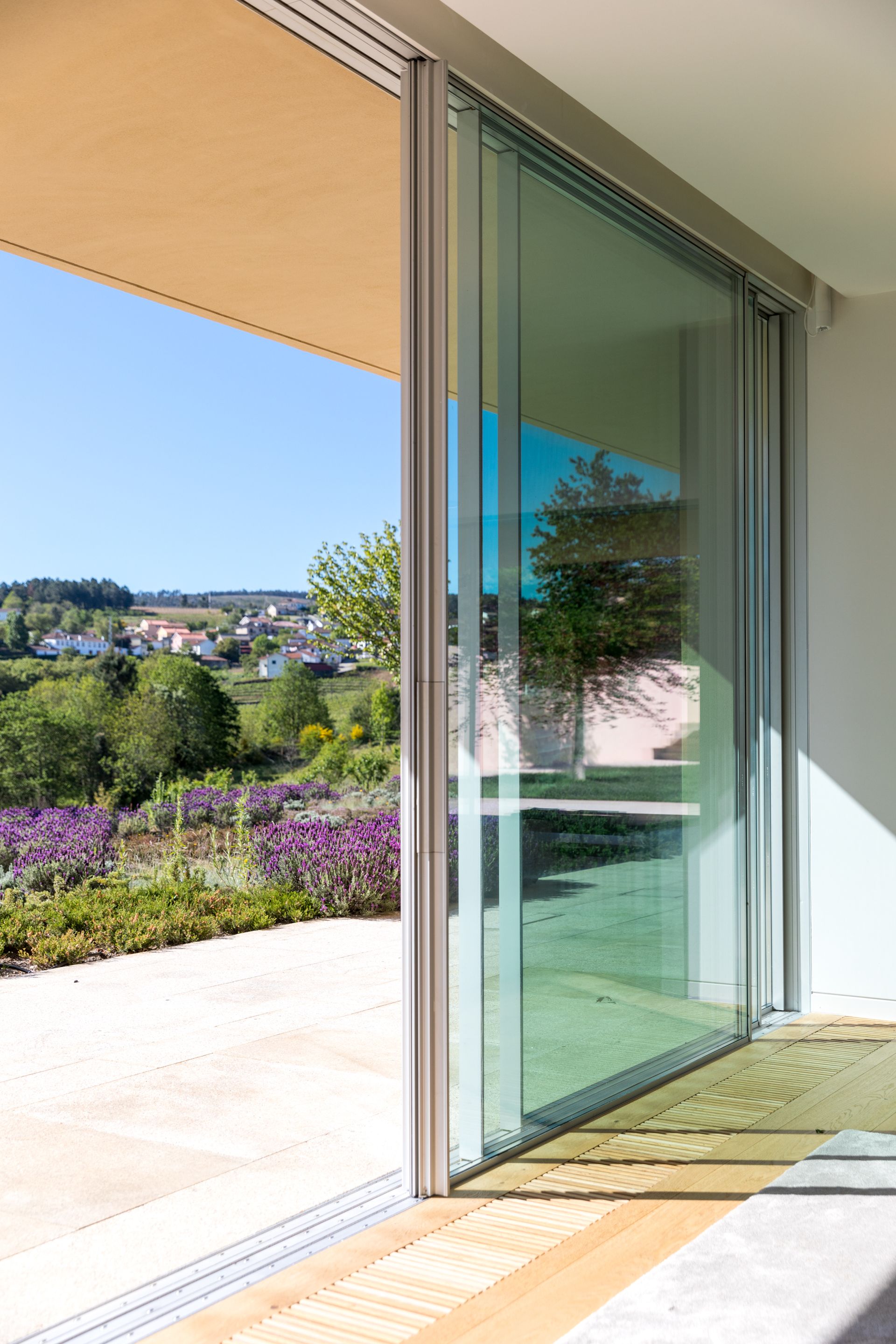 Modern living room with large sliding glass windows by Otiima, showcasing seamless indoor-outdoor transition.