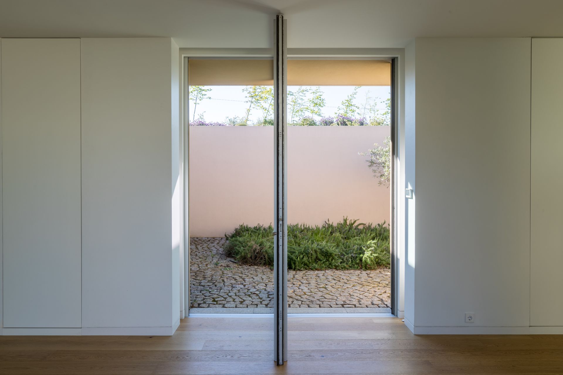 Modern room with a sliding door overlooking a garden. Minimalist window frame and architecture