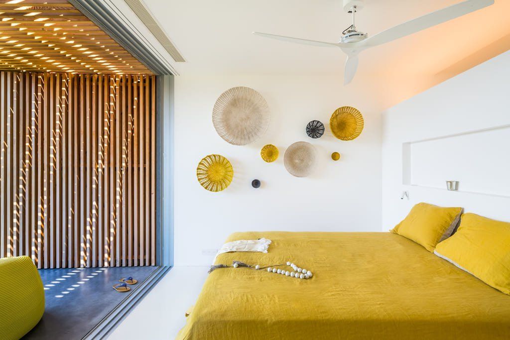 Bedroom with a minimalist window frame, bed sheets and yellow pillows in a modern environment