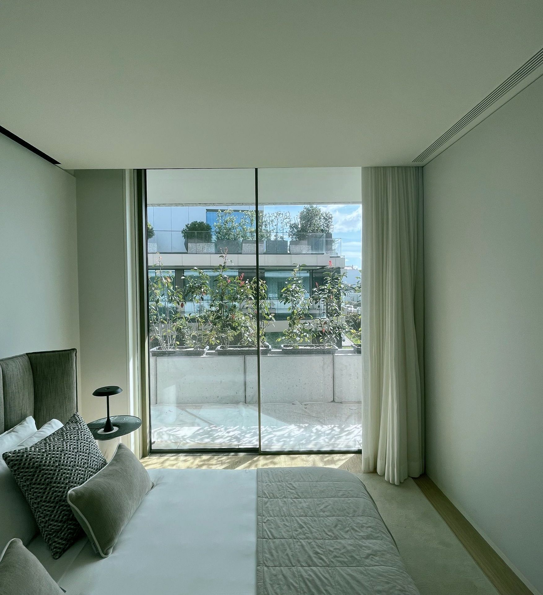 A modern living room in Greenstone with sleek furniture and expansive windows showcases the connection between the interior and the surrounding nature.