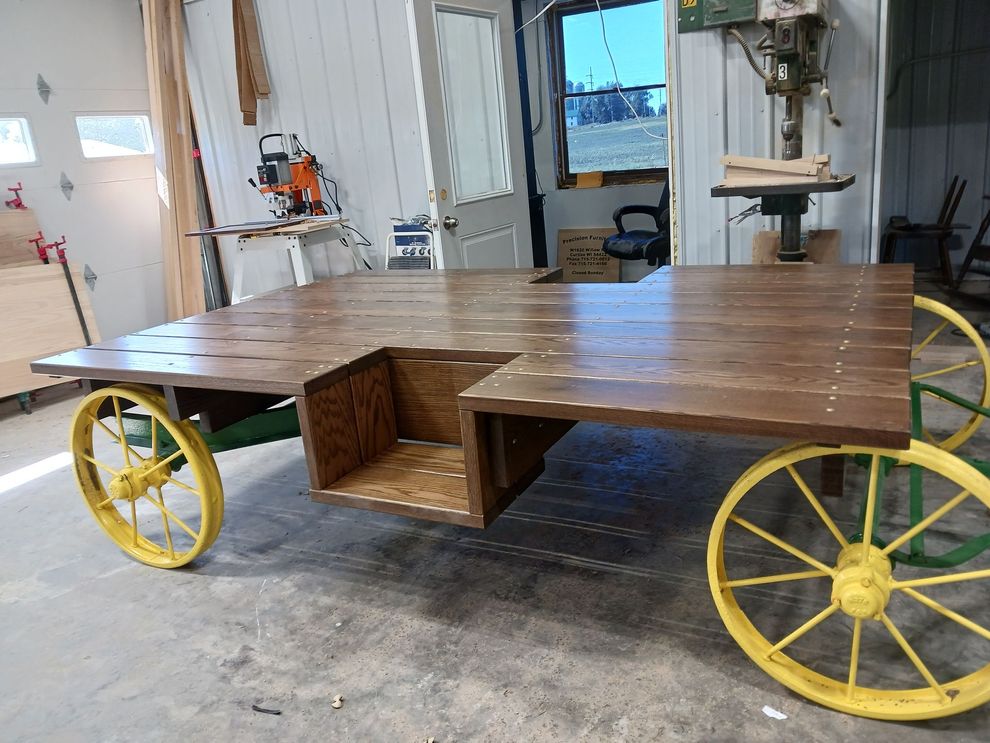 Large wooden work table on yellow wagon wheels in a workshop/garage