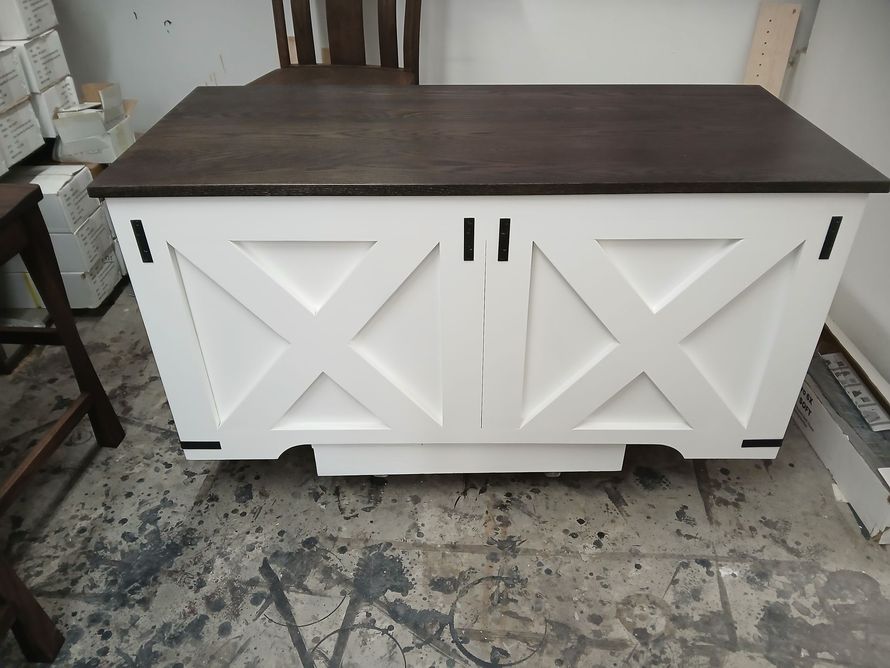 White barn-door storage cabinet with dark wood top in a workshop setting