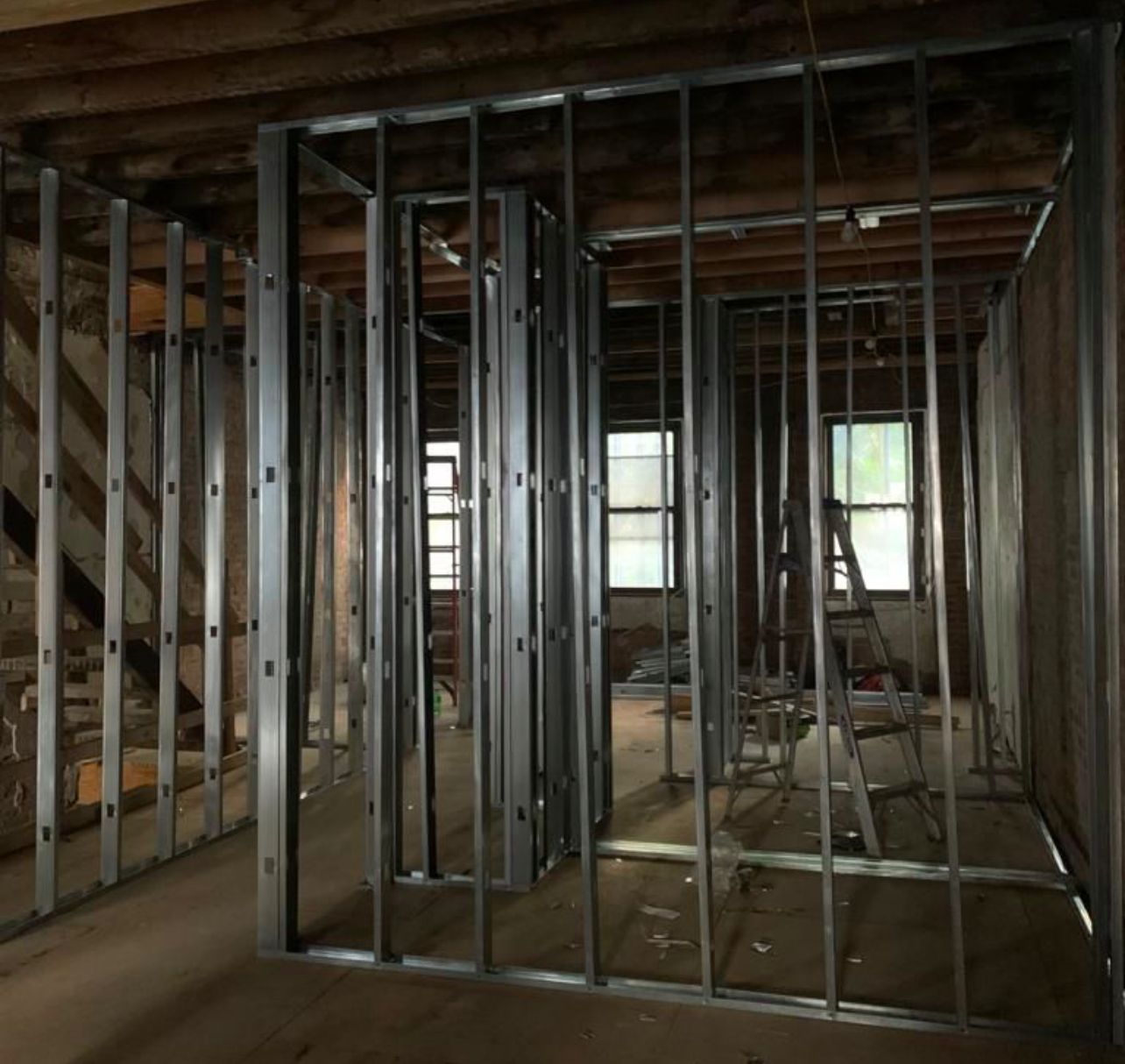 Metal stud framing for interior walls; renovation of a room with exposed wooden beams.