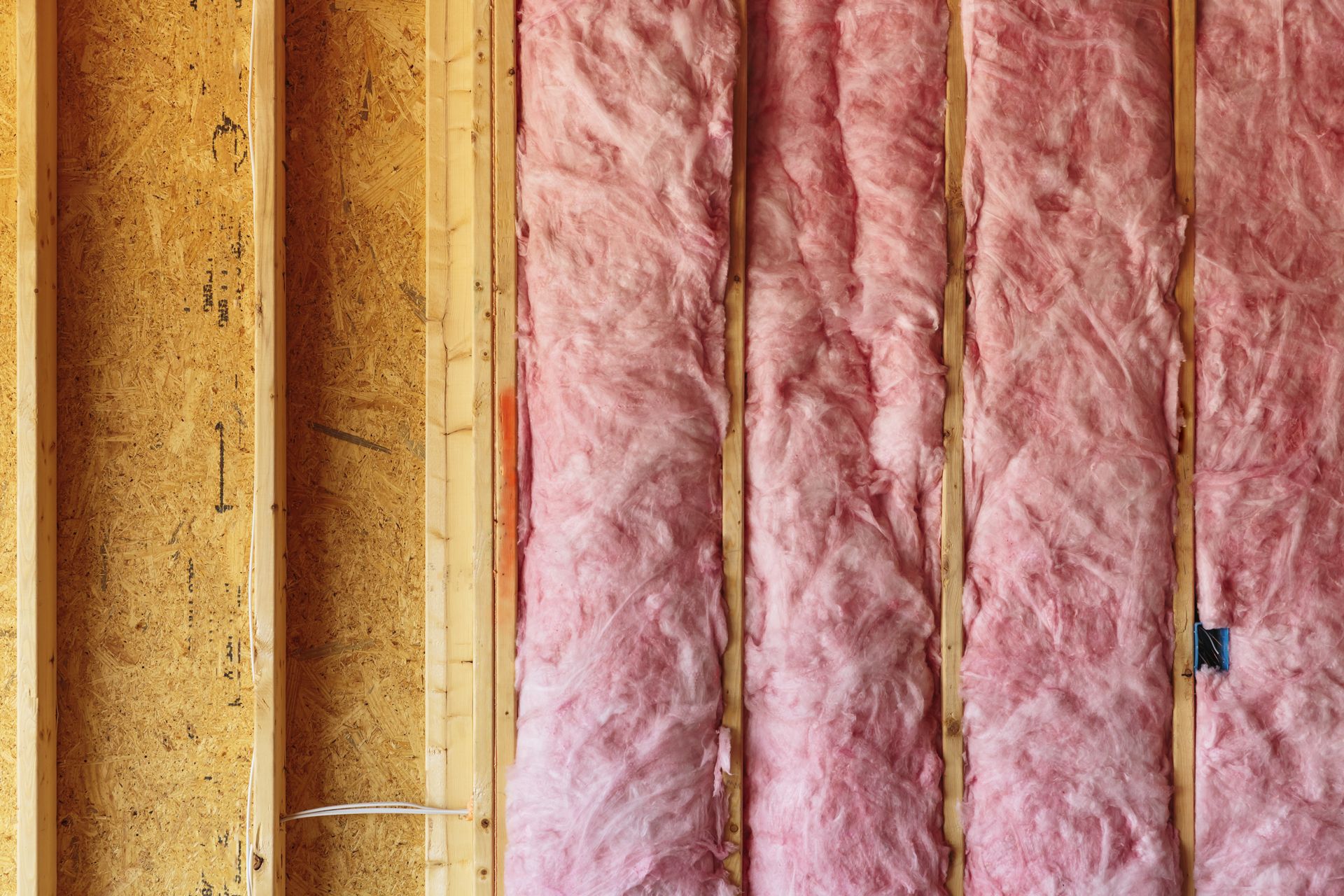 Wooden framing with pink insulation installed between the studs.