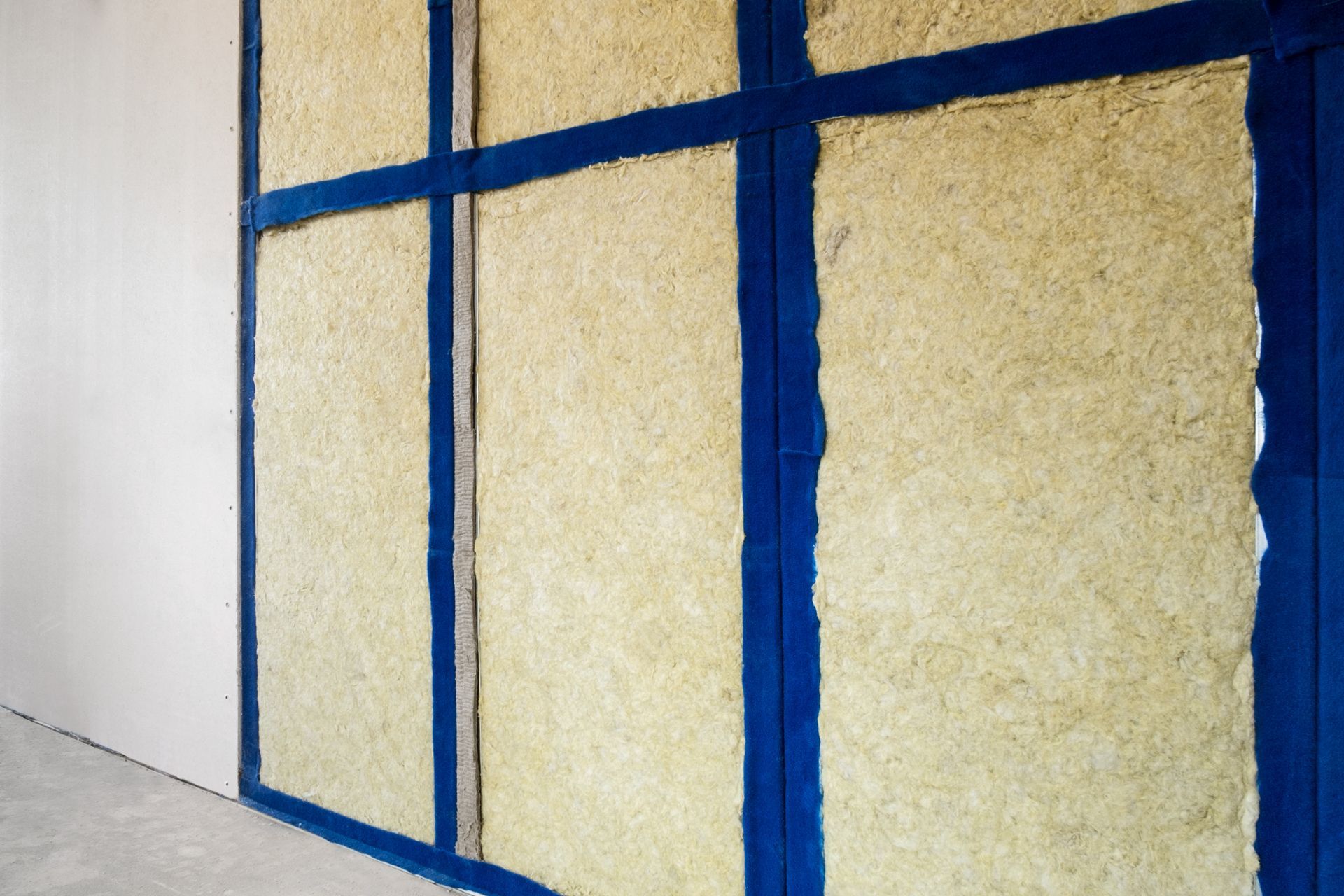 Insulation panels installed on a wall, framed by blue tape.