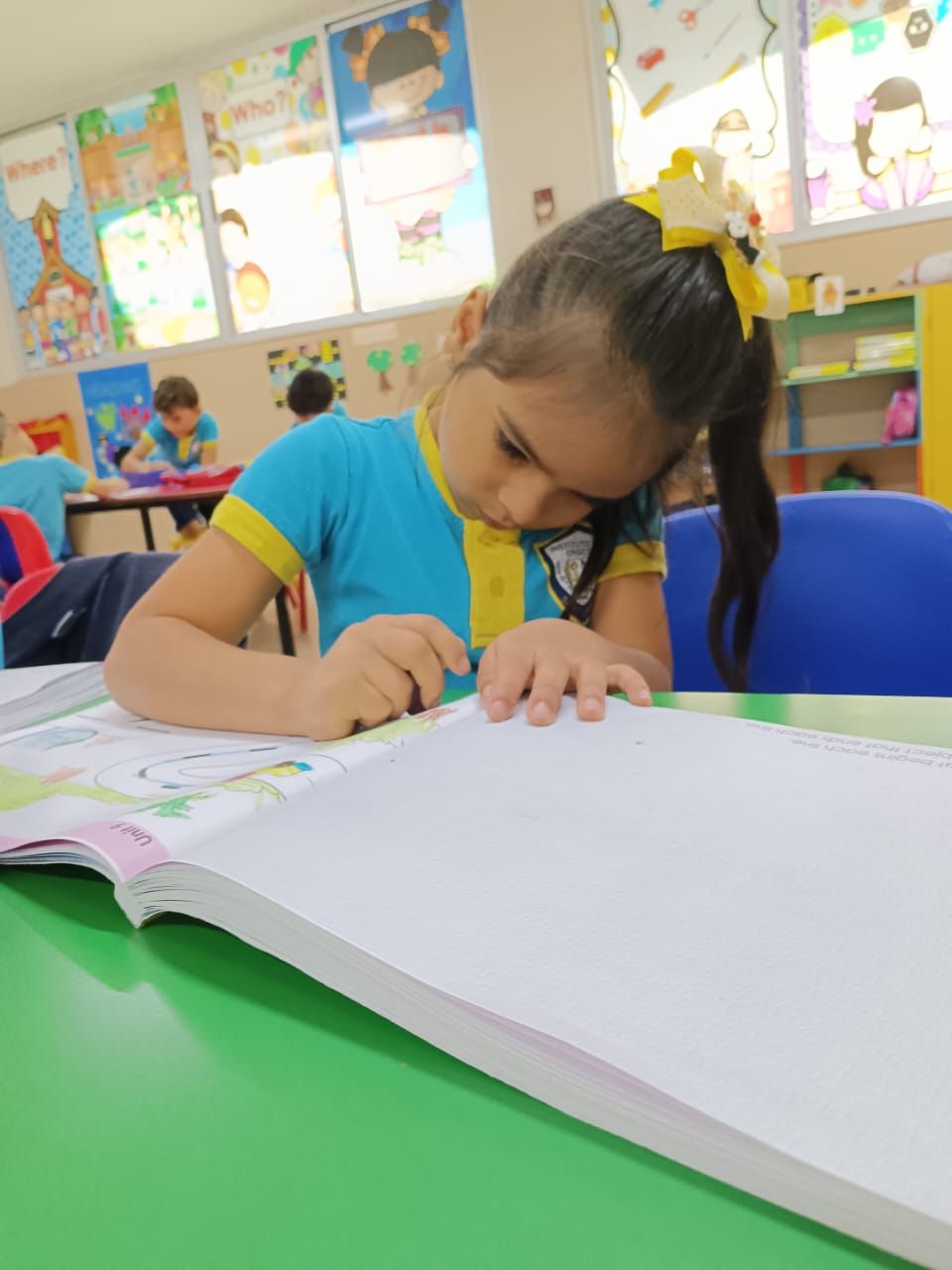 Una niña está sentada en una mesa leyendo un libro.