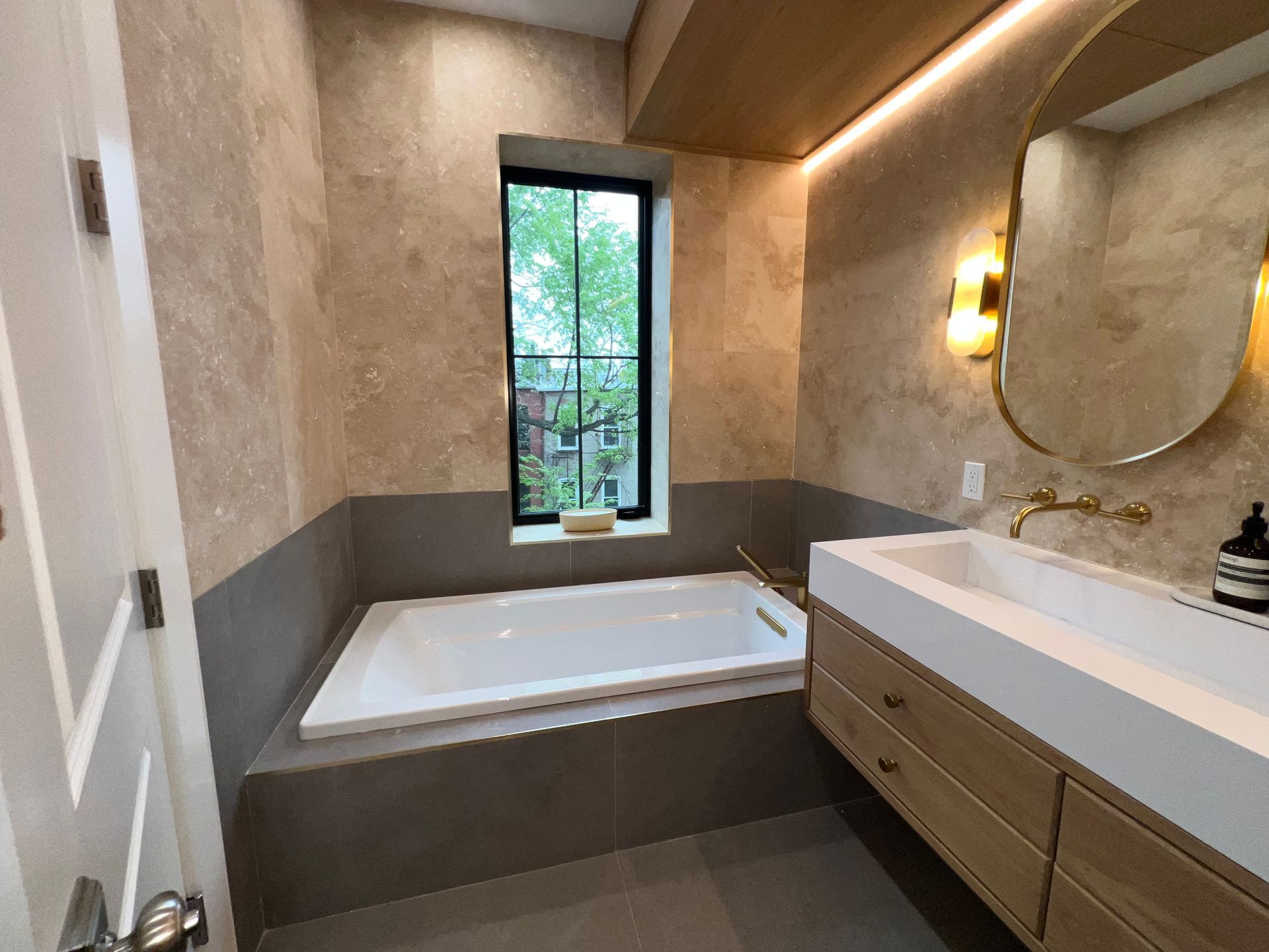 Modern bathroom with freestanding tub, double vanity, and window to greenery