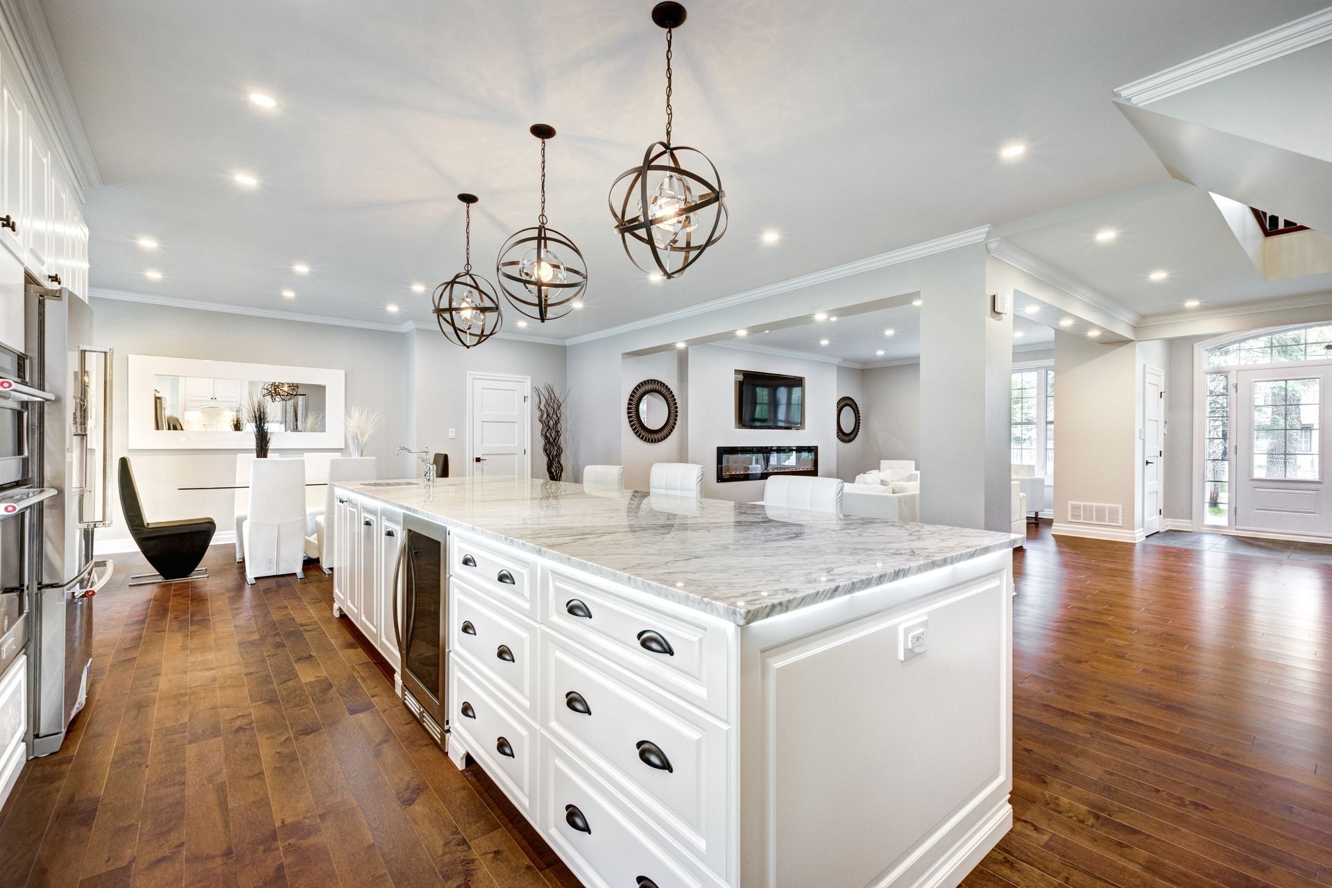 Bright modern kitchen with white cabinetry, large island, pendant lights, and hardwood floors