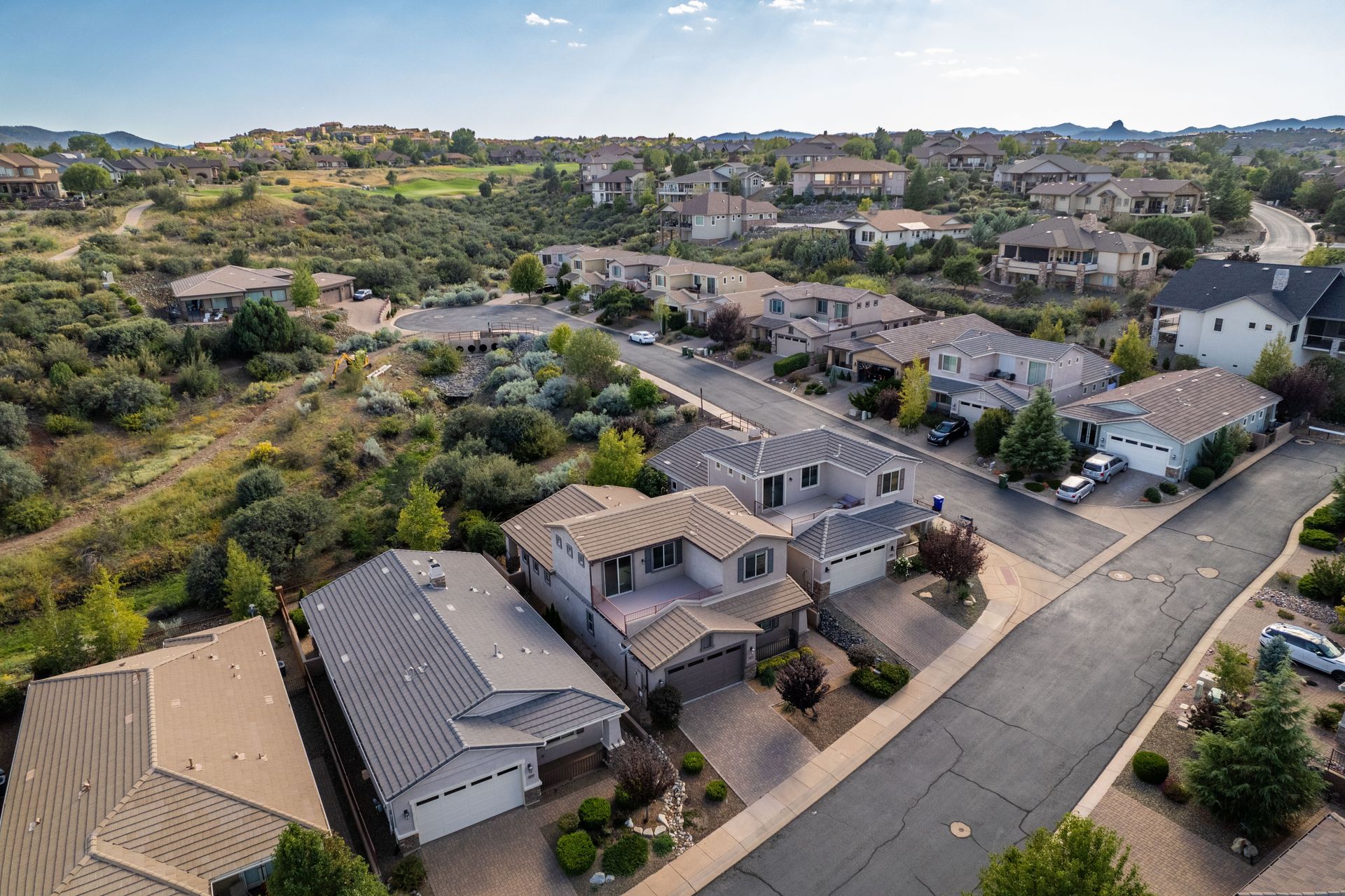 Aerial view of a quiet suburban neighborhood with houses, streets, and dry hillside vegetation