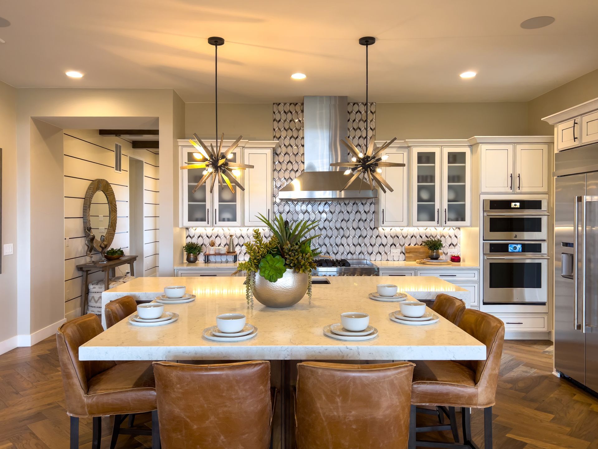 Bright modern kitchen and dining area with a wooden table, pendant lights, and white cabinets.
