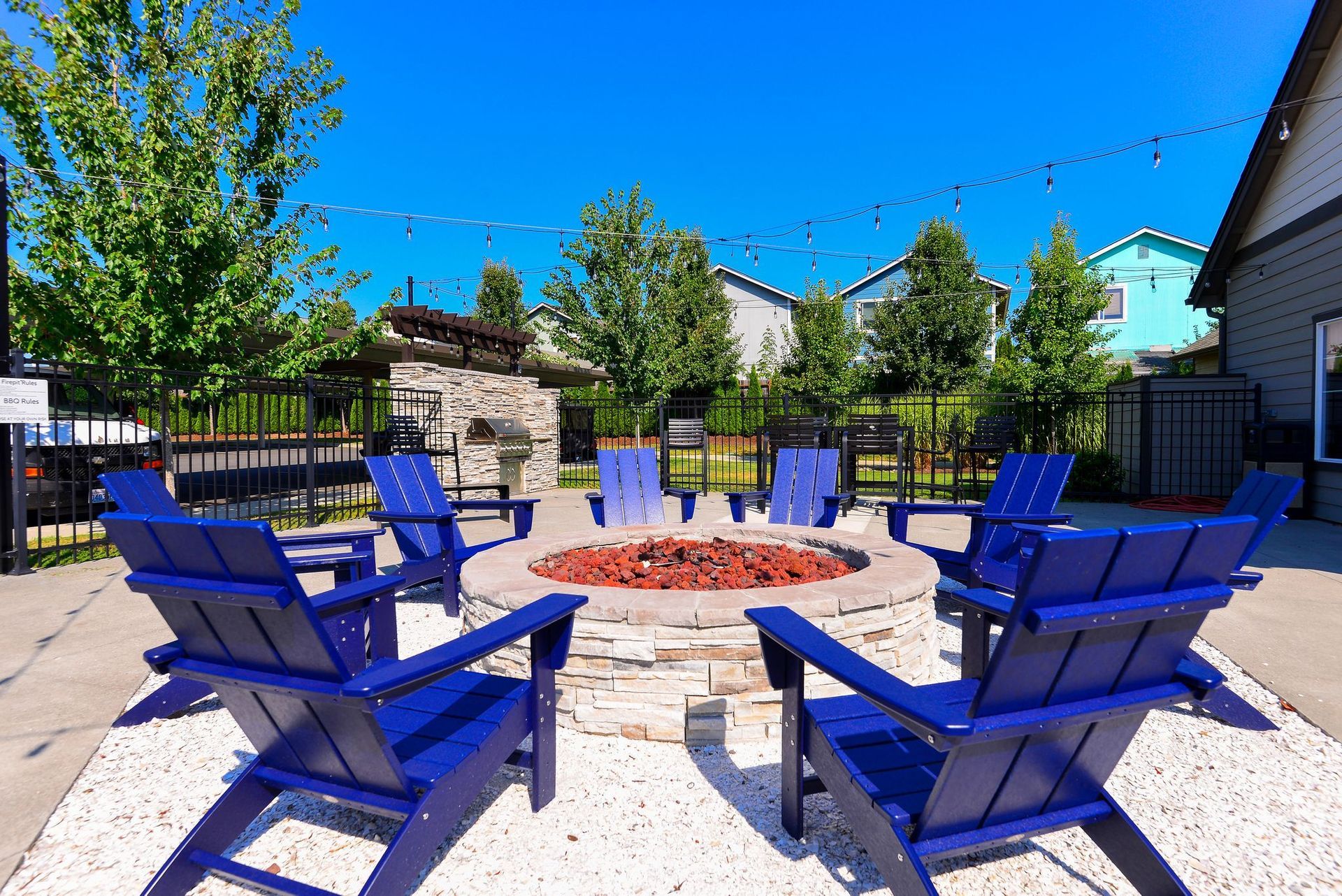 a group of blue chairs are sitting around a fire pit .
