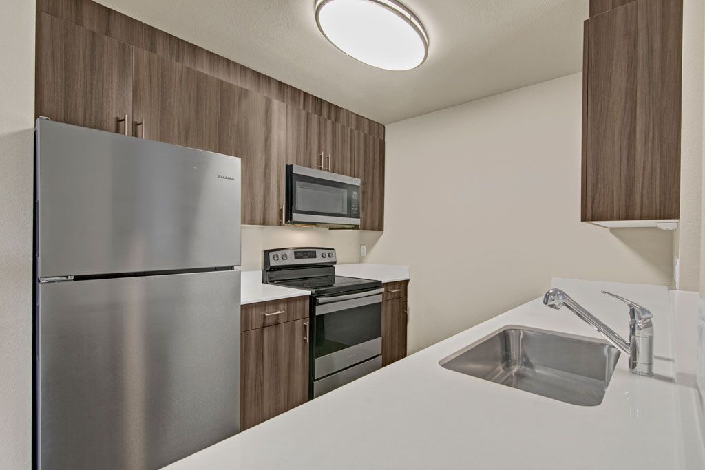 a kitchen with a sink , refrigerator , stove and microwave .