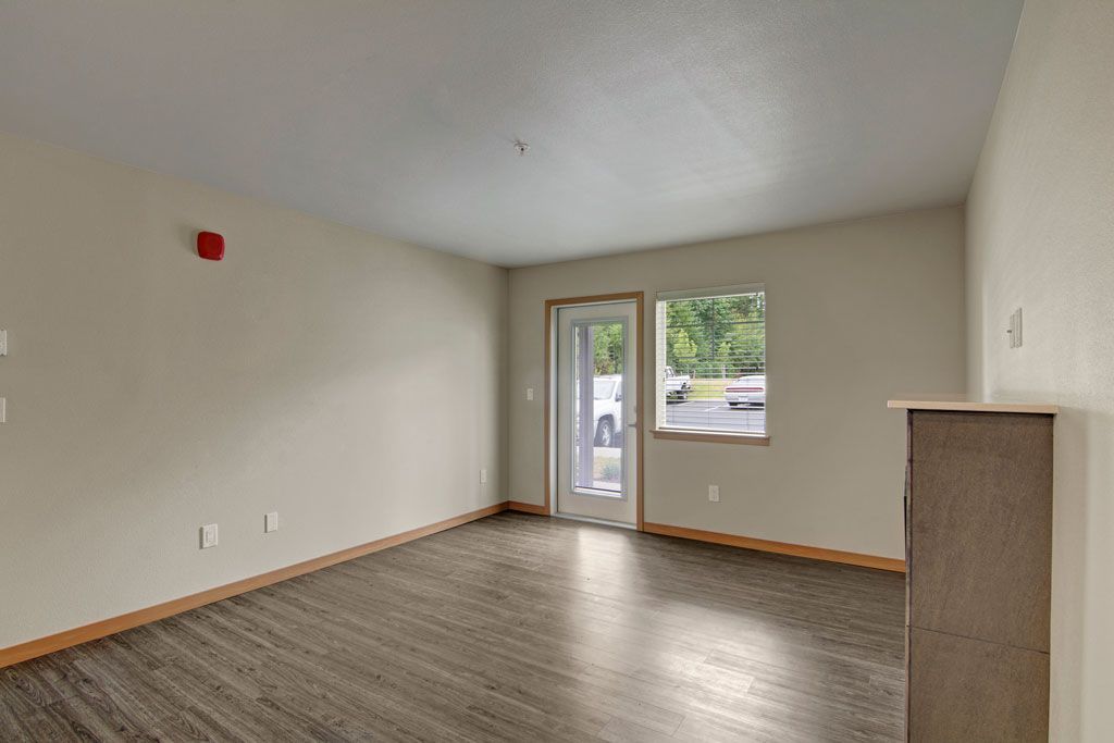 an empty living room with hardwood floors and a sliding glass door .