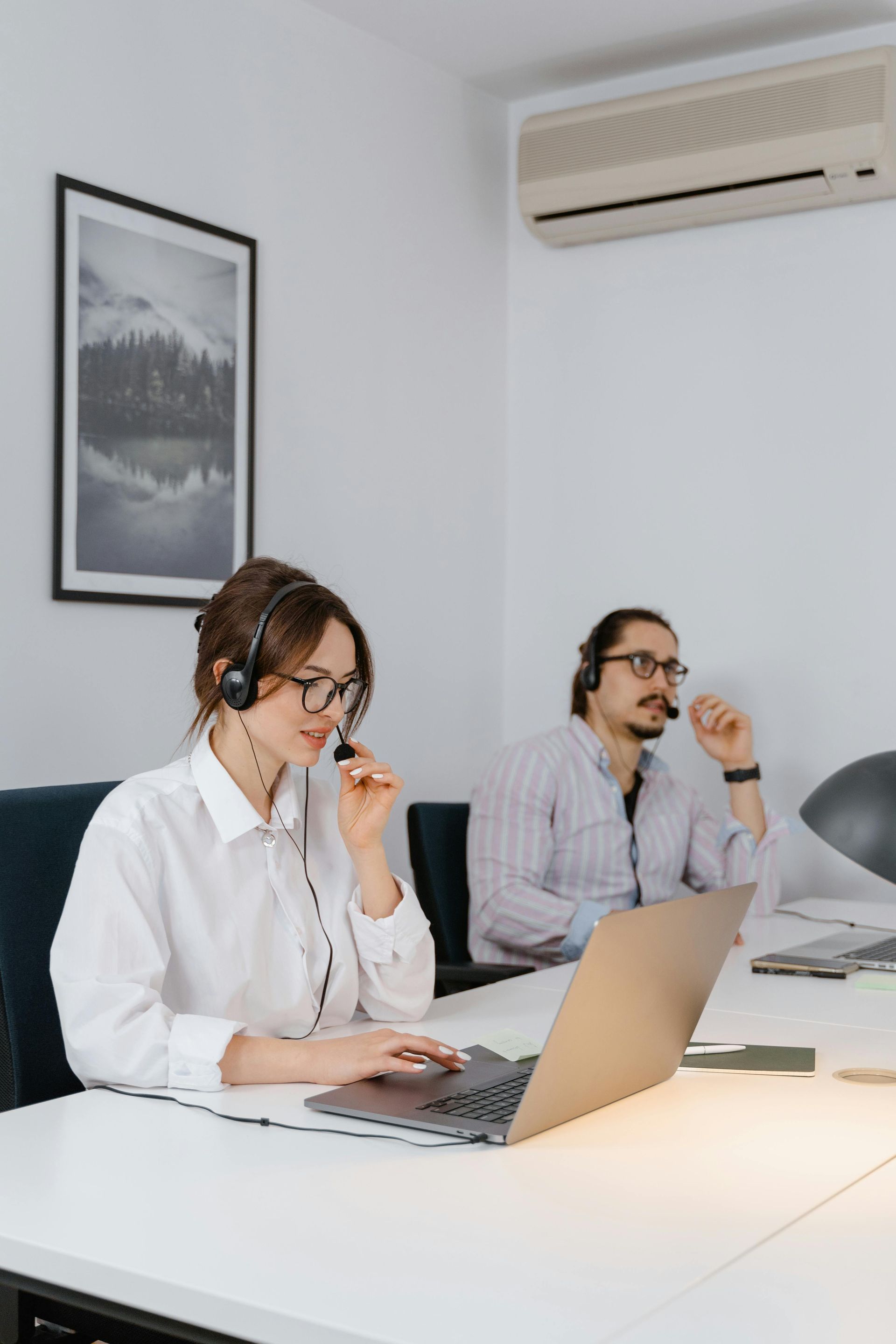 A woman wearing a headset is sitting at a desk with a laptop.